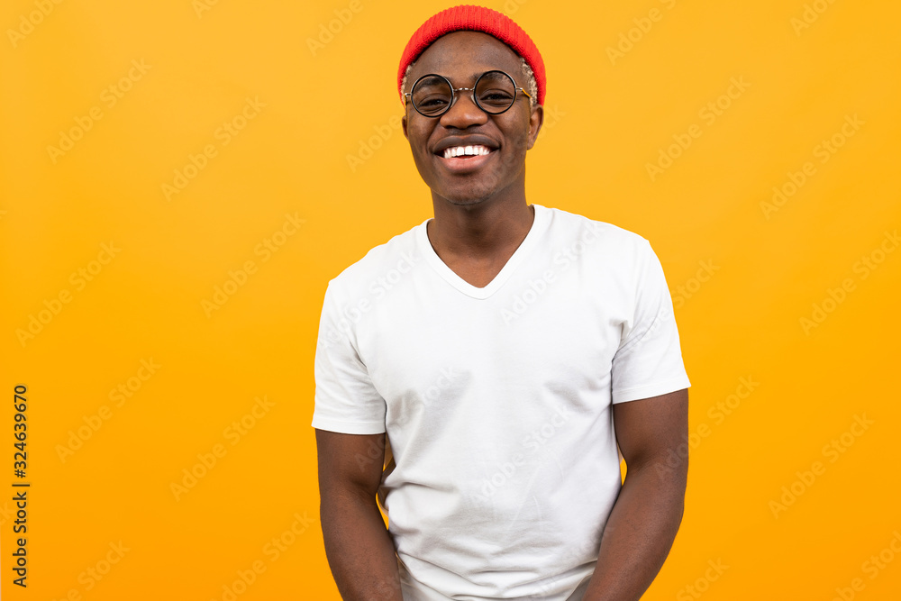 portrait of a stylish smiling sexy african black man in a white t-shirt with glasses on a yellow background portrait of a stylish smiling sexy african black man in a white t-shirt with glasses on a yellow background