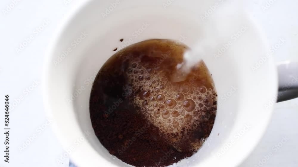 Making instant coffee. Top overhead view of water pouring into glass cup with instant coffee granules Making instant coffee. Top overhead view of water pouring into glass cup with instant coffee granules