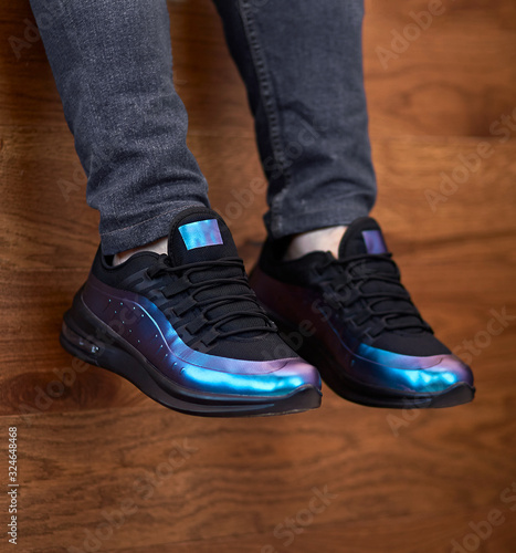 electric colored sport shoes hanging down on the wooden background © AlexGo