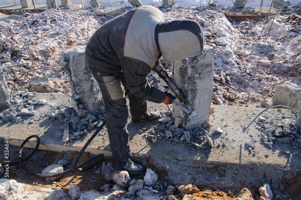 A worker works with a jackhammer at a construction site A worker works with a jackhammer at a construction site