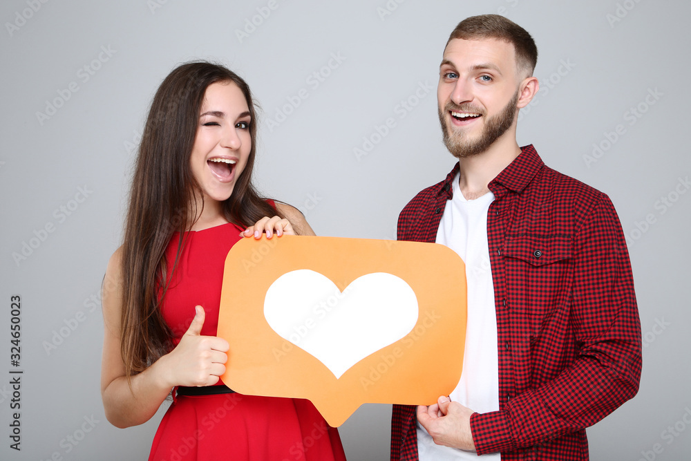 Happy young couple with paper heart on grey background Happy young couple with paper heart on grey background