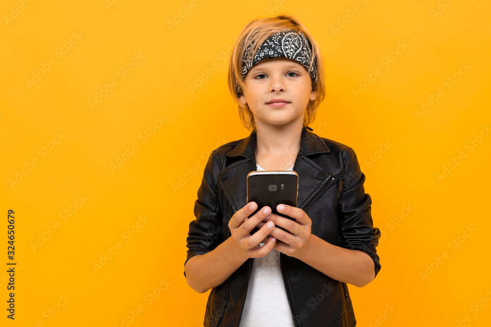 Stylish young boy in black jacket and white t-shirt serfing internet with his phone Stylish young boy in black jacket and white t-shirt serfing internet with his phone