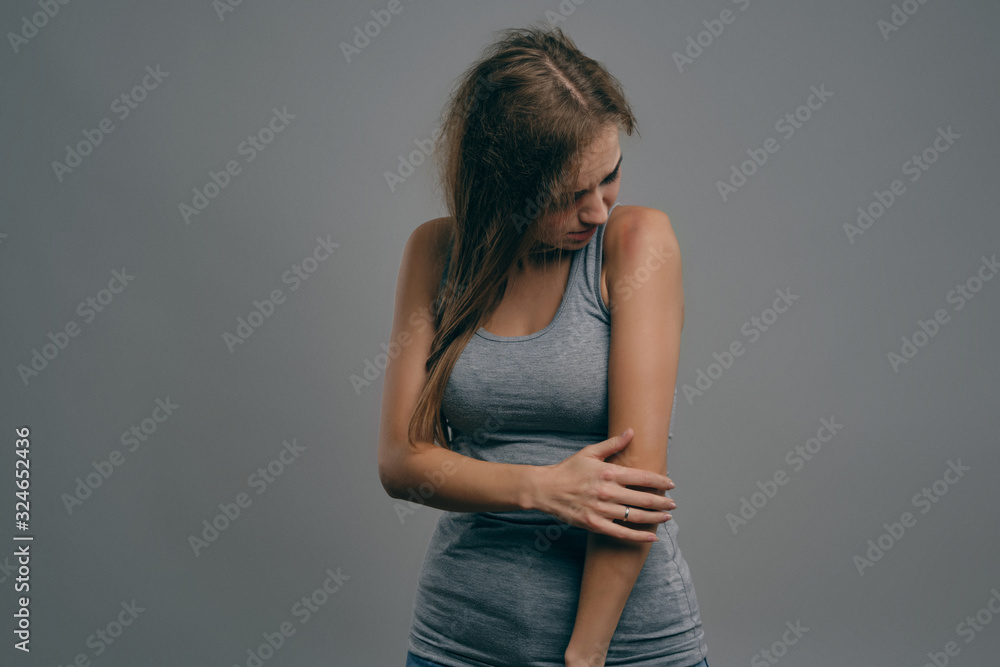 Blonde girl with bruises on her face posing against gray studio background. Domestic violence, abuse. Depression, despair. Close-up, copy space. Blonde girl with bruises on her face posing against gray studio background. Domestic violence, abuse. Depression, despair. Close-up, copy space.