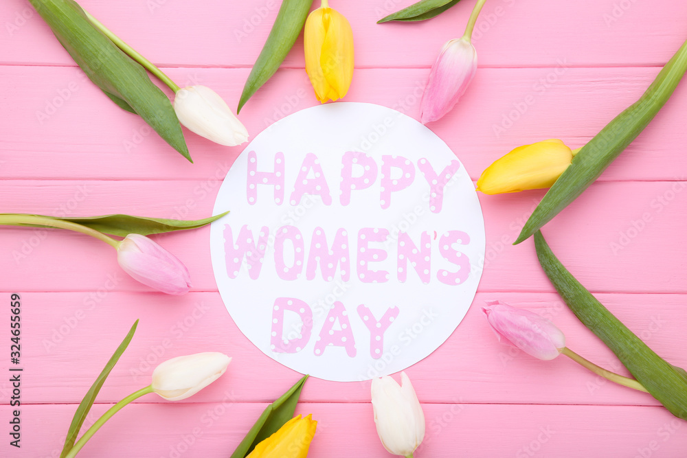 Text Happy Womens Day with tulip flowers on pink wooden table Text Happy Womens Day with tulip flowers on pink wooden table