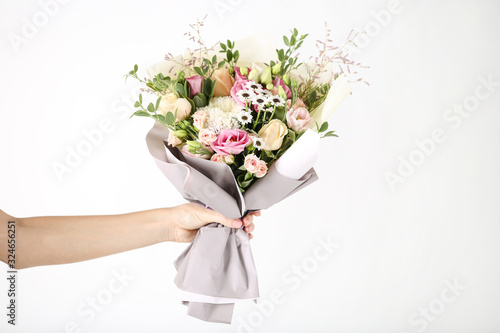 Female hand holding beautiful flower bouquet on white background