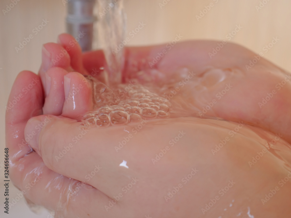 Fototapeta premium Beautiful woman washes her hands under the tap