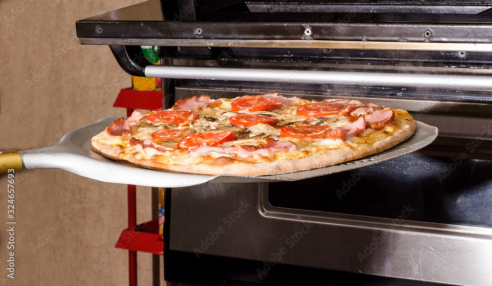 Cooking pizza in a pizzeria. Pizza is placed on a spatula in a baking