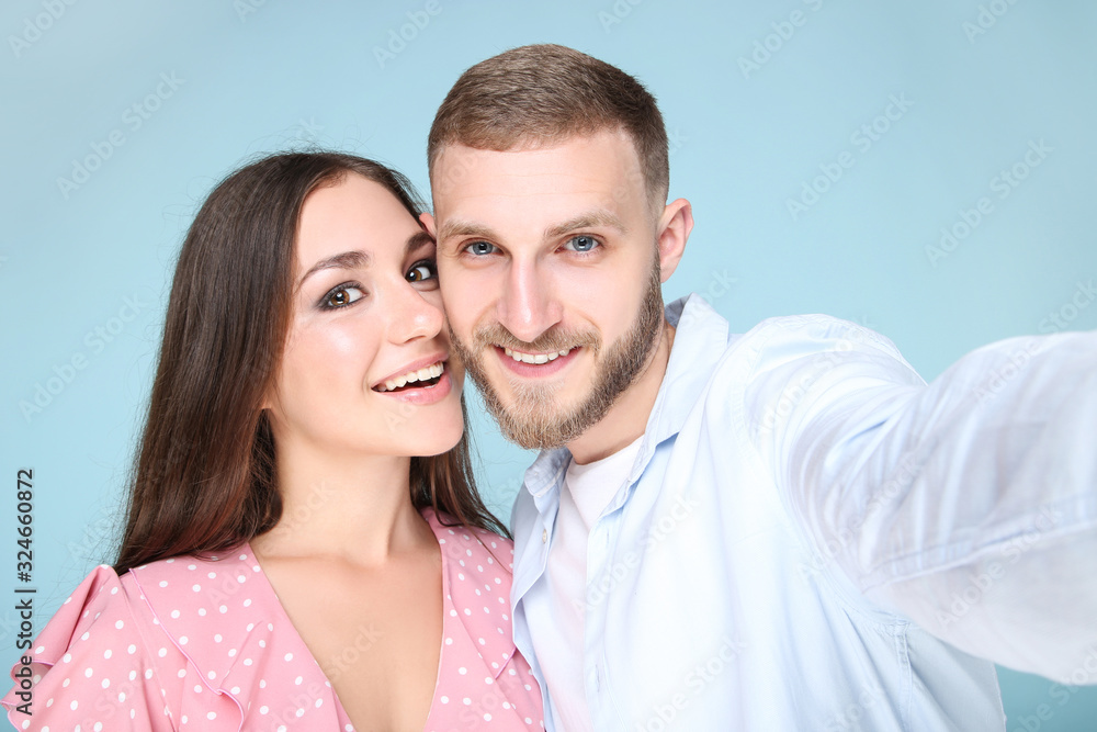Happy young couple making selfie on smartphone on blue background Happy young couple making selfie on smartphone on blue background