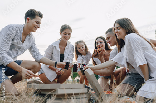 picnic friends with pizza and drinks drinking and eating with cheers  sunny day  sunset  company  fun  couples and mom with baby