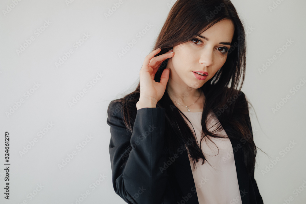 Young attractive emotional girl in business-style clothes on a plain white background in an office or audience Young attractive emotional girl in business-style clothes on a plain white background in an office or audience