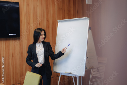 young emotional attractive girl in business-style clothes working with flipchart in a modern office or audience
