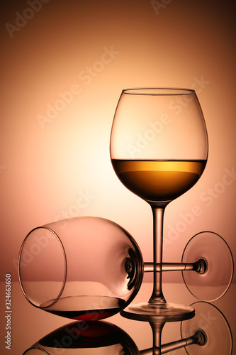 Two glasses with red and white wine, on a bright, colorful background, in backlight, photographed with light through the glass.