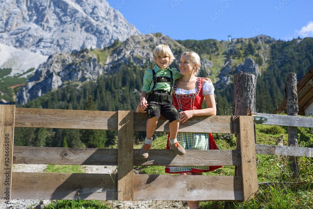 Young Bavarian family in a beautiful mountain landscape. Happy mother and little son in traditional Bavarian clothes