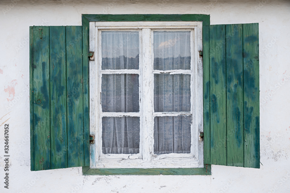 opened wooden window with green shutters, white facade
