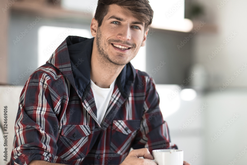 young man with a Cup of coffee in the background in the kitchen young man with a Cup of coffee in the background in the kitchen