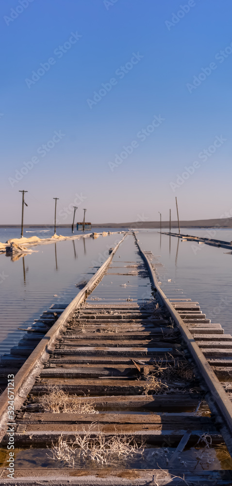 old rails sunk in water against a blue sky