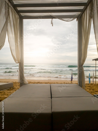 Toned image of sunbed under canopy at luxurious beach resort at ocean