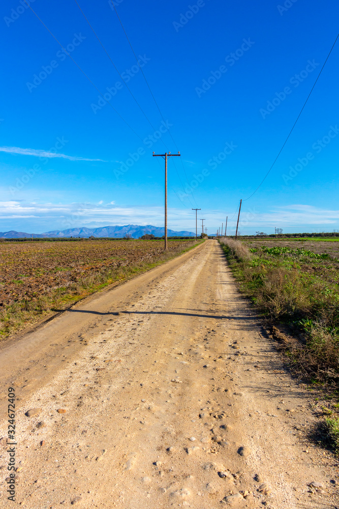 Scenic empty dirt road with traditional wooden electricity pylons at Xanthi regional unit, Greece, near Porto Lagos in winter Scenic empty dirt road with traditional wooden electricity pylons at Xanthi regional unit, Greece, near Porto Lagos in winter