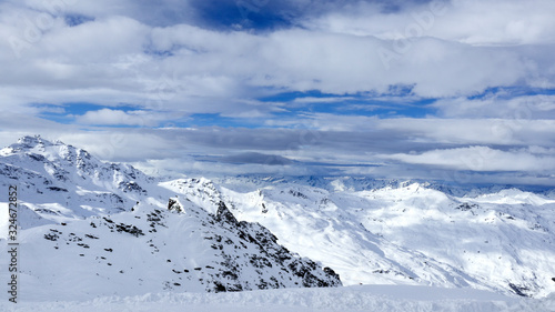 Panoramic view of alpine peaks covered with snow under low clouds, 3 Valleys Val Thorens winter resort, Alps, France .