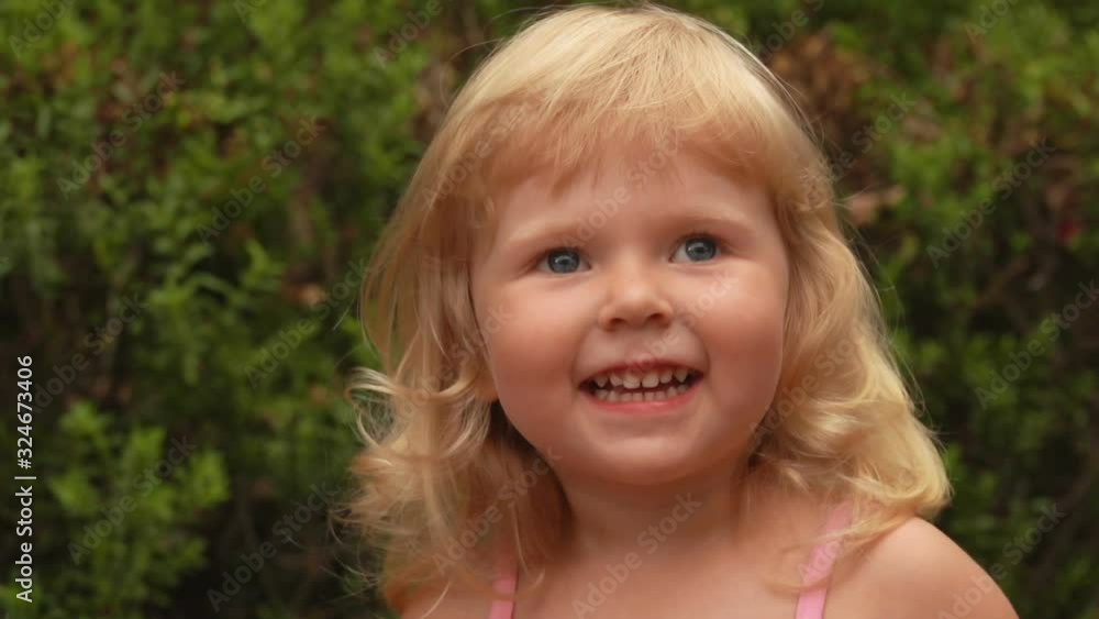 Portrait of a beautiful little blond girl smiling and laughing in sunny park outdoors Portrait of a beautiful little blond girl smiling and laughing in sunny park outdoors