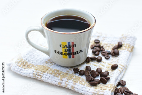 Traditional cup of Colombian coffee with coffee beans on wooden background
