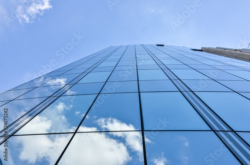 White clouds and blue sky reflected in the windows of the modern office building. Abstract background for business purposes.