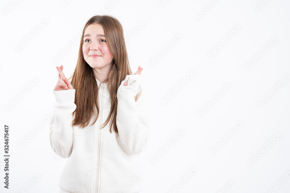 Pleased cheerful brunette woman puts all efforts in wishing good luck, crosses fingers, has faith for better, dressed in oversized hoodie, isolated over pink background Pleased cheerful brunette woman puts all efforts in wishing good luck, crosses fingers, has faith for better, dressed in oversized hoodie, isolated over pink background