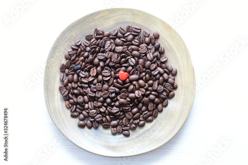  Processed coffee beans and tostao, with red heart on wooden background