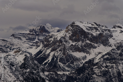 Cime e vette alpine di montagna formazioni rocciose riprese da lontano paesaggio naturale nuvoloso in inverno photo