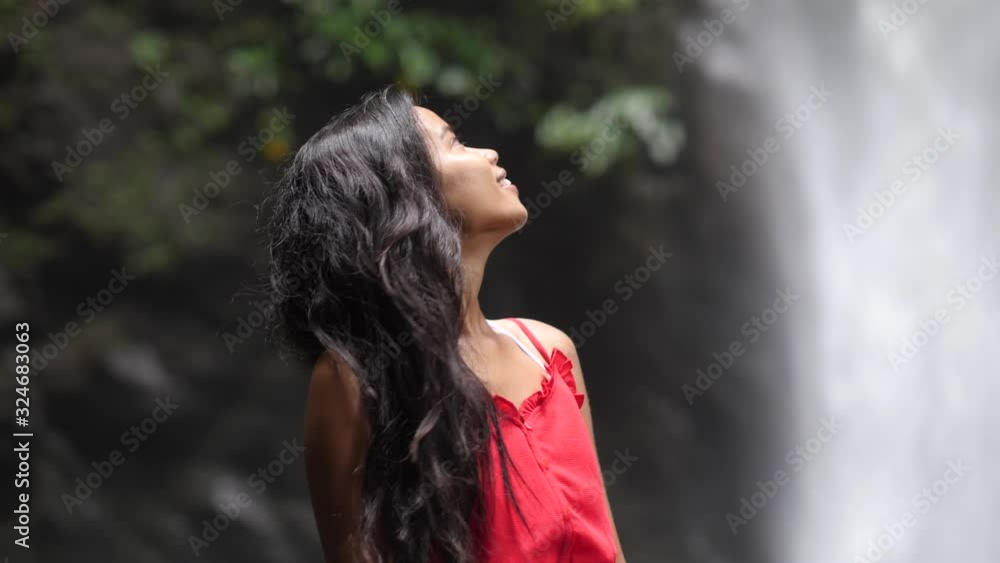 Half body shot of young and smiling woman with unfocused waterfall background. Half body shot of young and smiling woman with unfocused waterfall background.