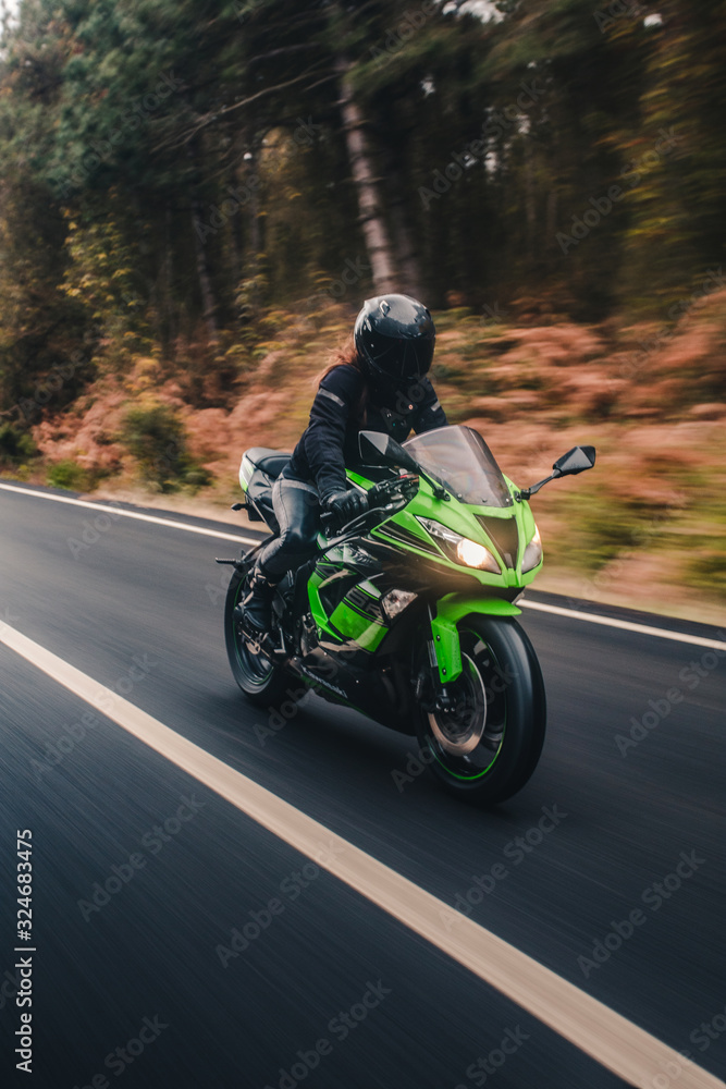 Biker biking a green motorcycle in the forest road Biker biking a green motorcycle in the forest road