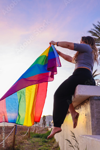 Happy lesbian girl showing flag at the beach.