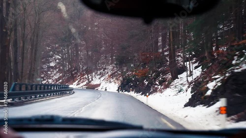 man rides behind the wheel of a car on a mountain serpentine in winter photo