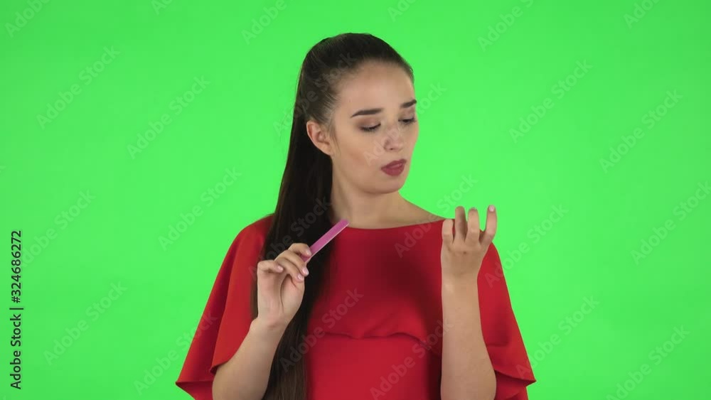 Portrait of pretty young woman is making herself manicure with pink nail file. Green screen Portrait of pretty young woman is making herself manicure with pink nail file. Green screen