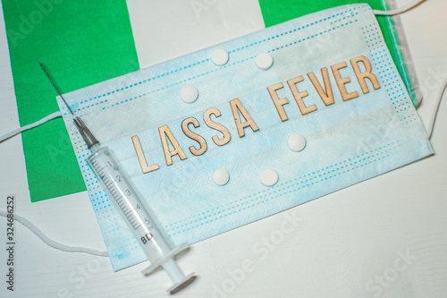 Nigerian flag under words Lassa fever outbreak concept. protective breathing mask and syringe. Lassa hemorrhagic fever LHF endemic in West Africa including Sierra Leone, Liberia, Guinea and Nigeria photo