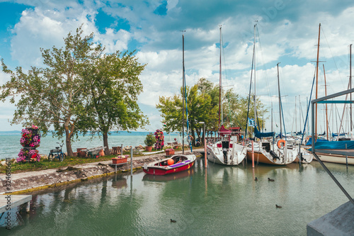View to entrance to Siofok harbor at Balaton lake, Hungary, with crystal clear water of emerald color, green coastline, puffy clouds on sky