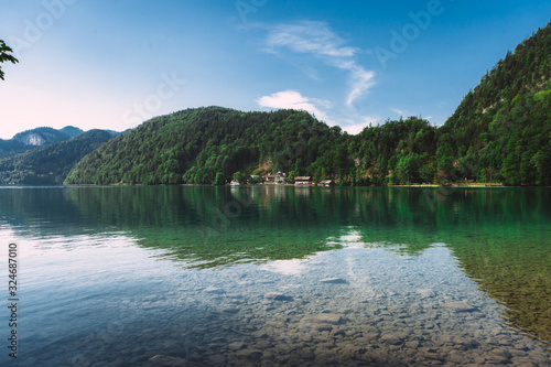 Fototapeta Naklejka Na Ścianę i Meble -  Panoramic view of idyllic summer landscape in the Alps with clear mountain lake and fresh green mountain pastures in the background. Postcard picture.