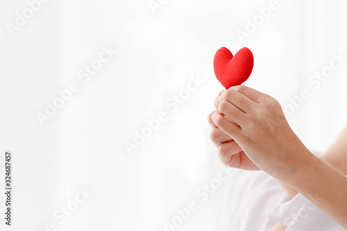 Close up woman s hand holding red heart with copy space on left side.