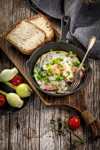 Fried eggs with ham on an old wooden background.