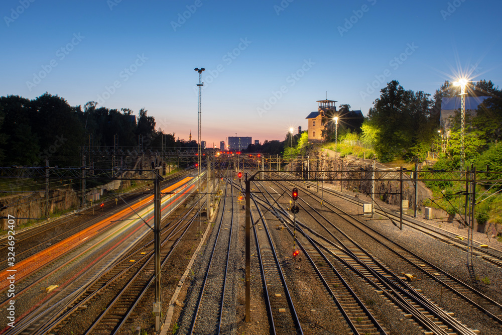 Fototapeta premium train leaving light trails on rail yard junction at sunset