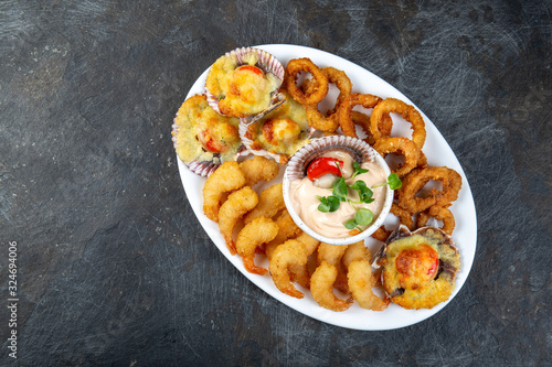 PERUVIAN FOOD. Piqueo caliente. Hot seafood platter fried shrimps, squid rings and baked scallops with sauce