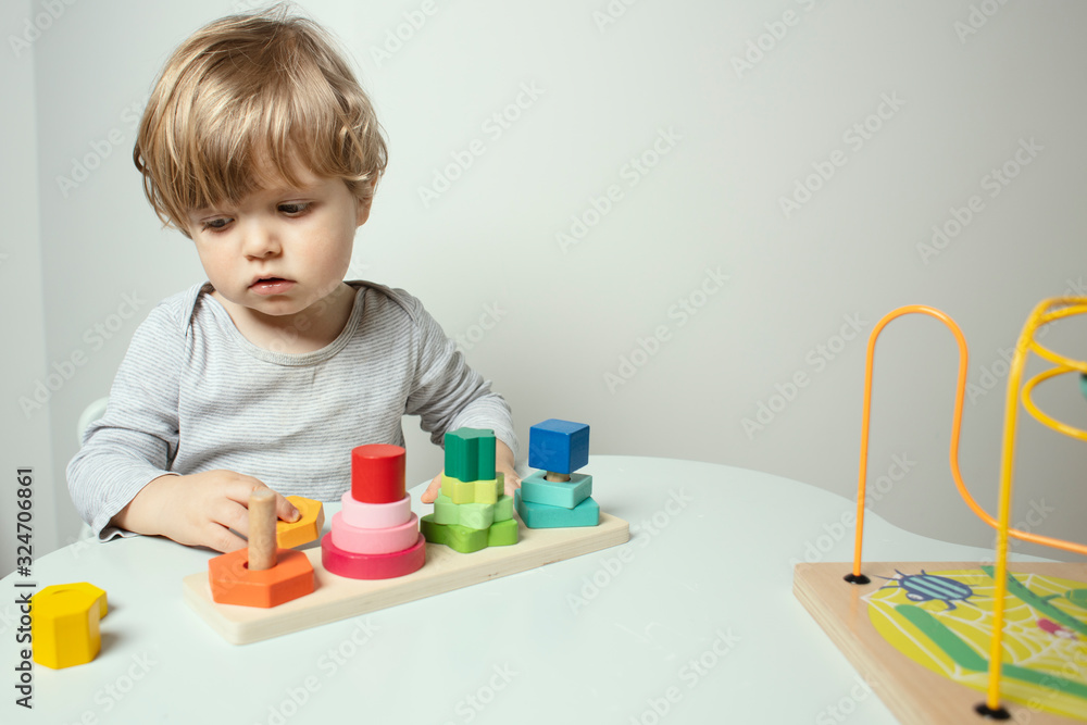 Beautiful toddler play with a wooden toys at home. Toddler play with a color educational toy. Child play at the table in the baby room. Child development. Funny baby. Lifestyle. Beautiful toddler play with a wooden toys at home. Toddler play with a color educational toy. Child play at the table in the baby room. Child development. Funny baby. Lifestyle.
