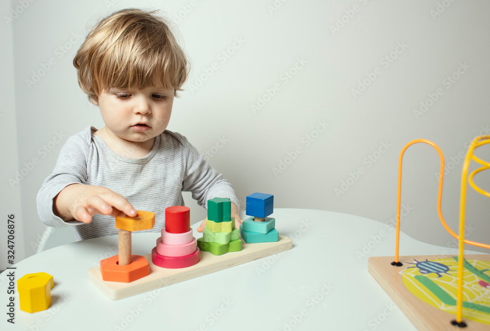 Beautiful toddler play with a wooden toys at home. Toddler play with a color educational toy. Child play at the table in the baby room. Child development. Funny baby. Lifestyle. Beautiful toddler play with a wooden toys at home. Toddler play with a color educational toy. Child play at the table in the baby room. Child development. Funny baby. Lifestyle.