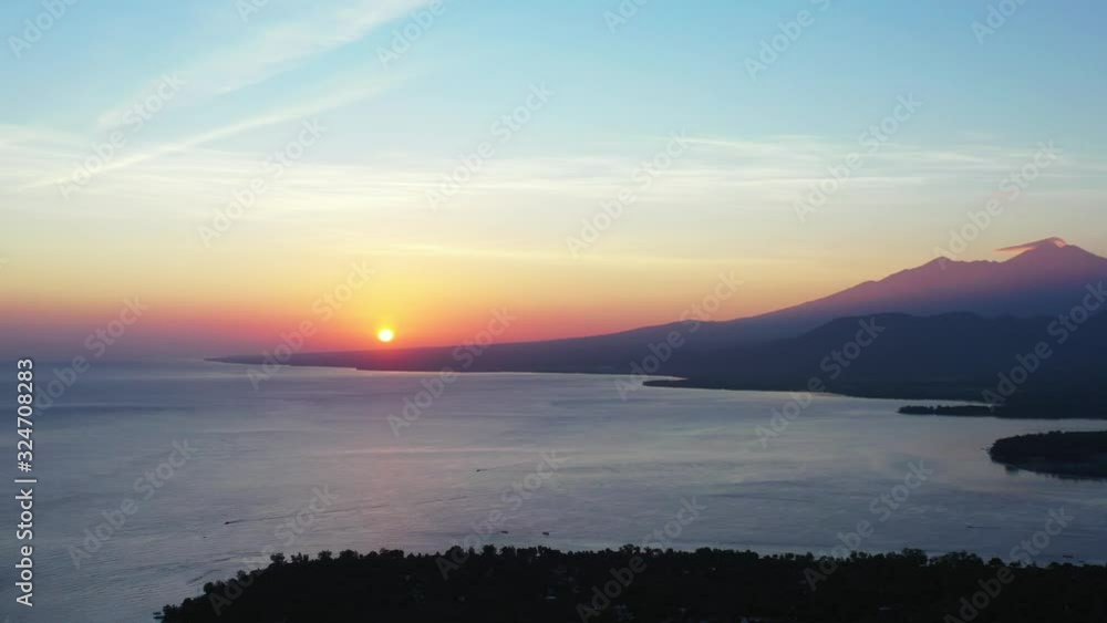 Bali Indonesia, Beautiful misty purple sunset, the golden sun setting behind the mountain island. Bali Indonesia, Beautiful misty purple sunset, the golden sun setting behind the mountain island.