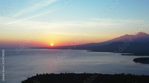 Bali Indonesia, Beautiful misty purple sunset, the golden sun setting behind the mountain island. photo