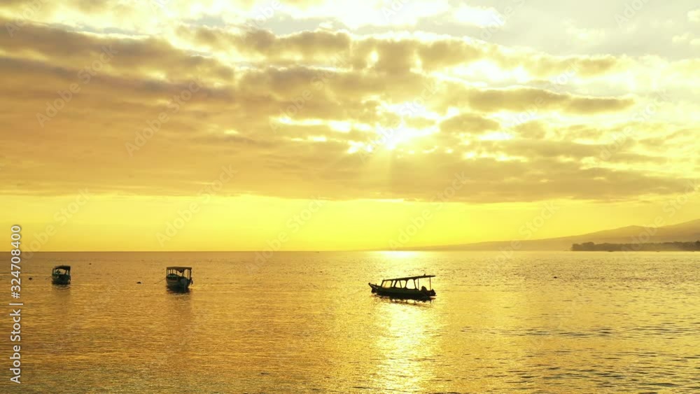 Traditional Balinese fishing boats floating on the calm sea. Beautiful golden sun coming out through the fluffy clouds. tropical sunset Traditional Balinese fishing boats floating on the calm sea. Beautiful golden sun coming out through the fluffy clouds. tropical sunset