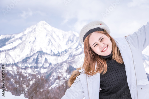 Young woman smiling with white coat and white hat on snow mountain background.