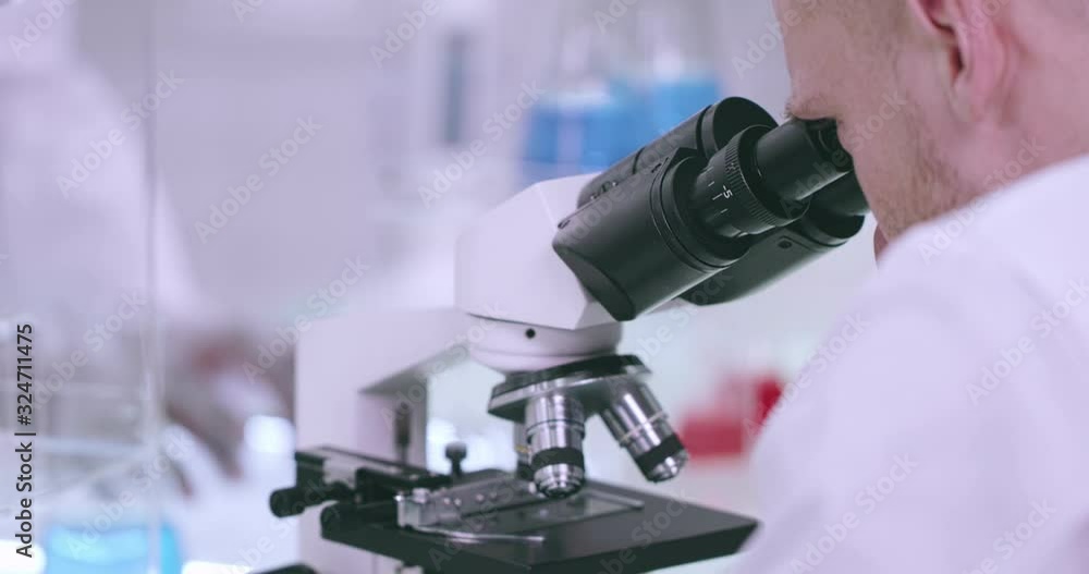 Man working in laboratory looks into a microscope Man working in laboratory looks into a microscope