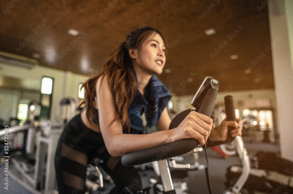 Front view of woman workout with bike. Women exercise working out in the gym for healthy lifestyle on bike at sunset. fitness ,workout, gym exercise ,lifestyle and healthy concept. Front view of woman workout with bike. Women exercise working out in the gym for healthy lifestyle on bike at sunset. fitness ,workout, gym exercise ,lifestyle and healthy concept.