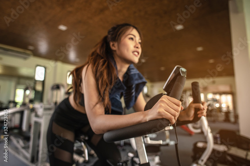 Front view of woman workout with bike. Women exercise working out in the gym for healthy lifestyle on bike at sunset. fitness  workout  gym exercise  lifestyle  and healthy concept.